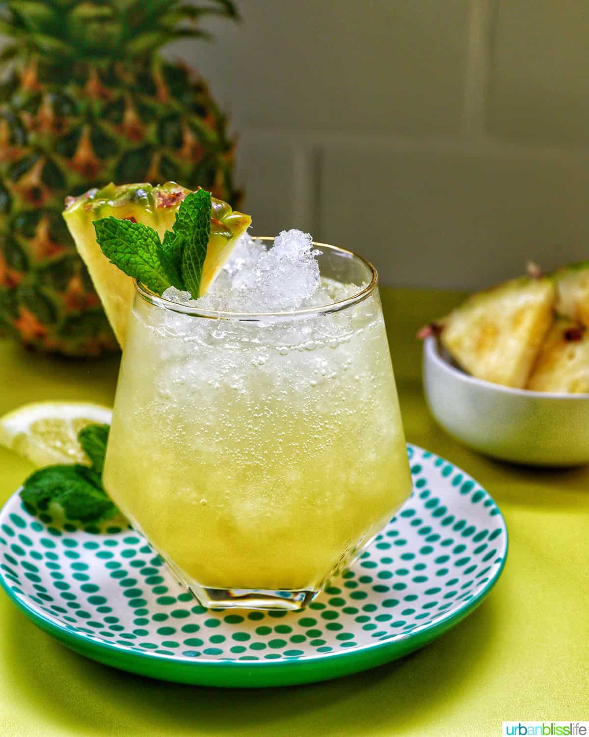 glass of pineapple mocktail with mint leaves and pineapple slice garnish.