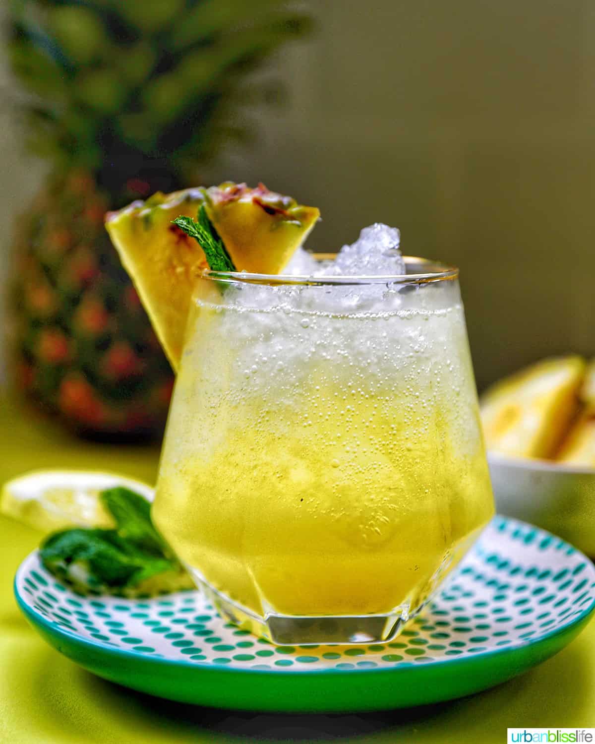 glass of pineapple mocktail with mint leaves and pineapple slice garnish.