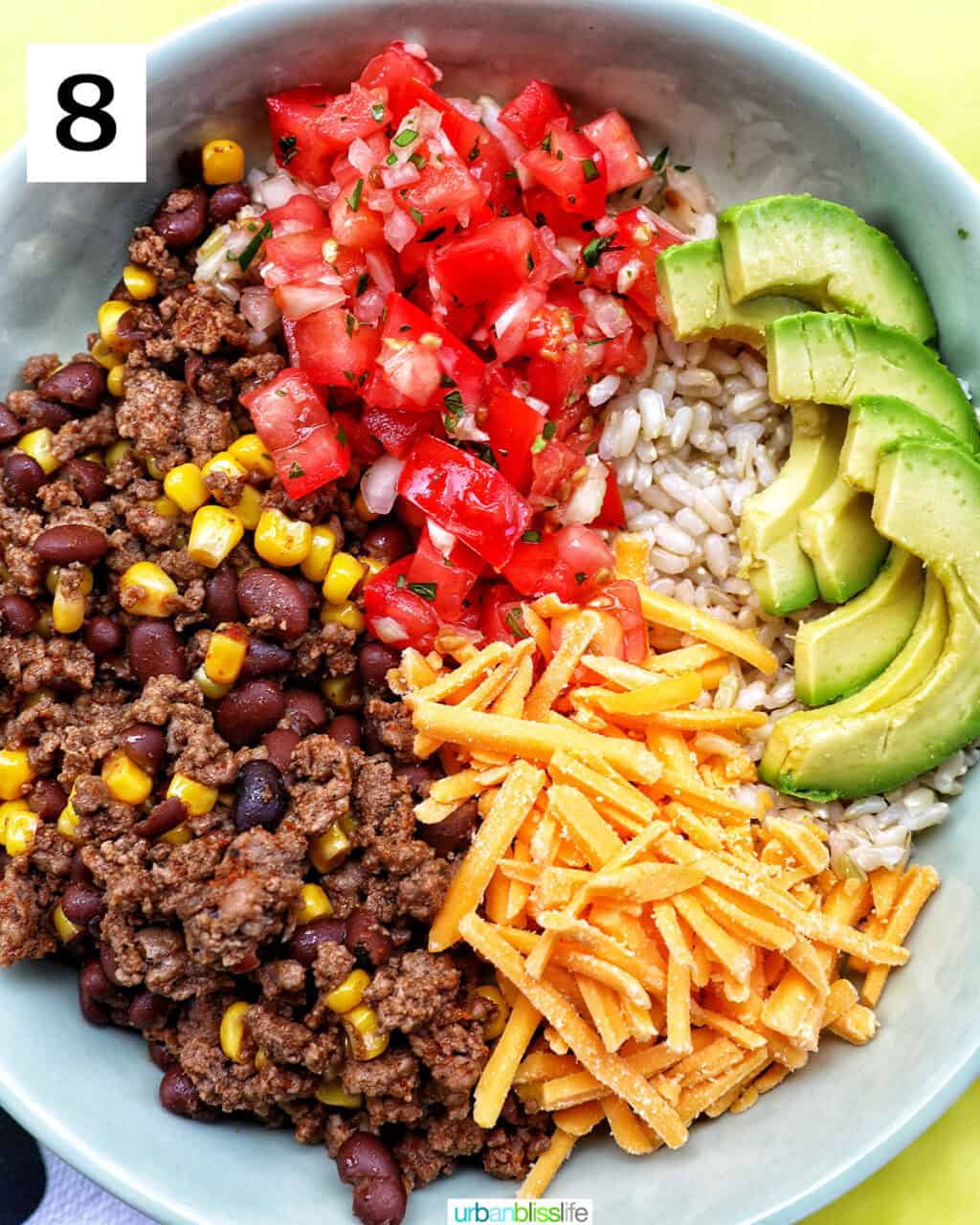 taco bowl of brown rice, beef, beans, corn, tomatoes, cheese, avocado.