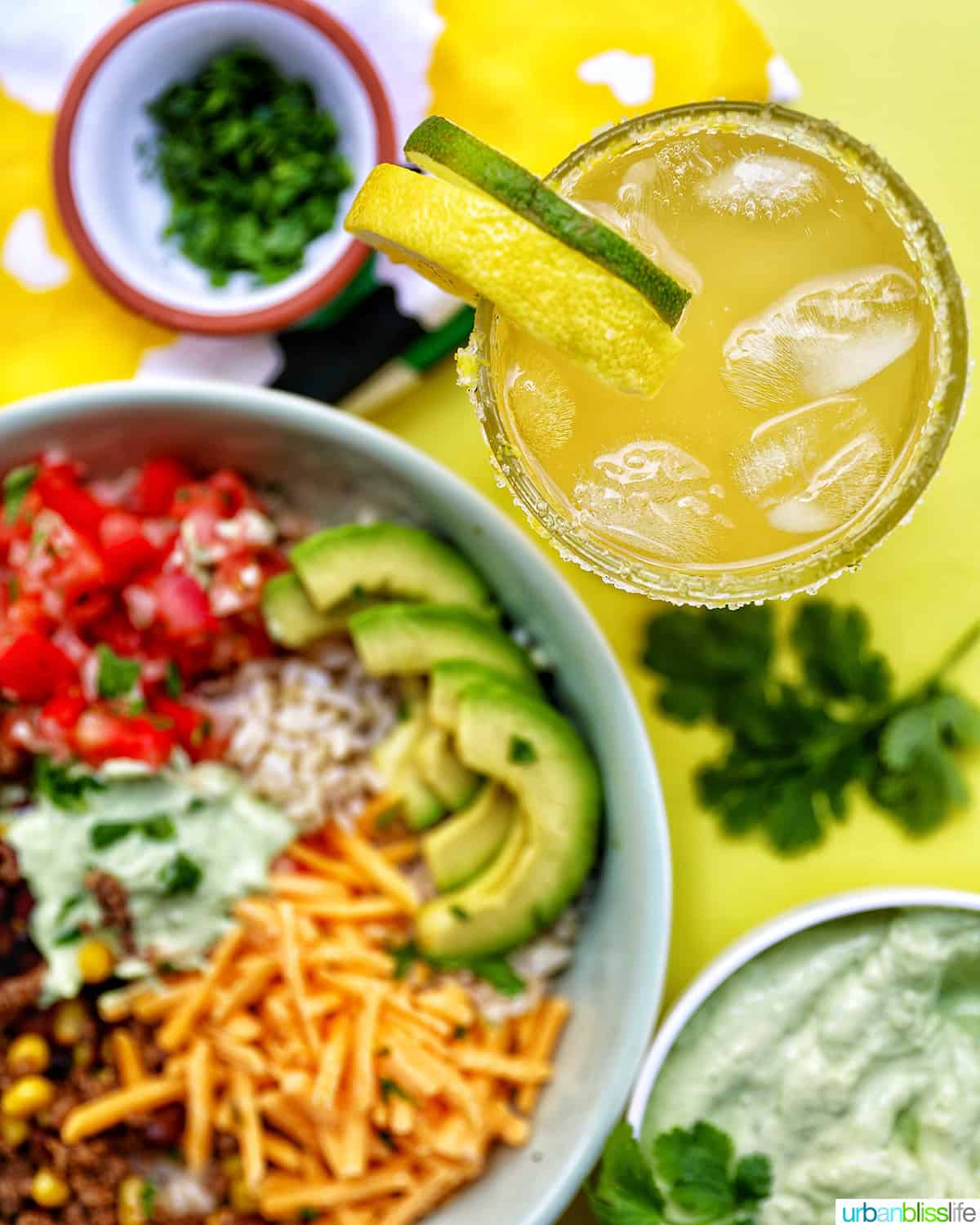taco bowl with glass of yuzu margarita and garnishes.