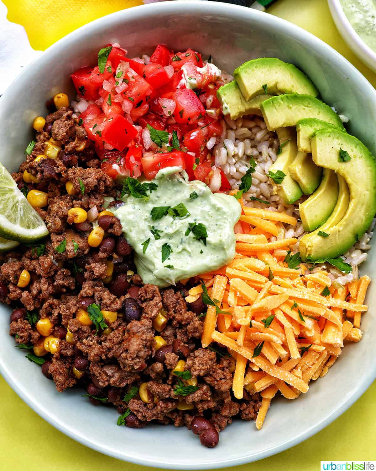 taco bowl with ground beef, beans, cheese, pico de gallo, avocado, rice, avocado cilantro lime crema.