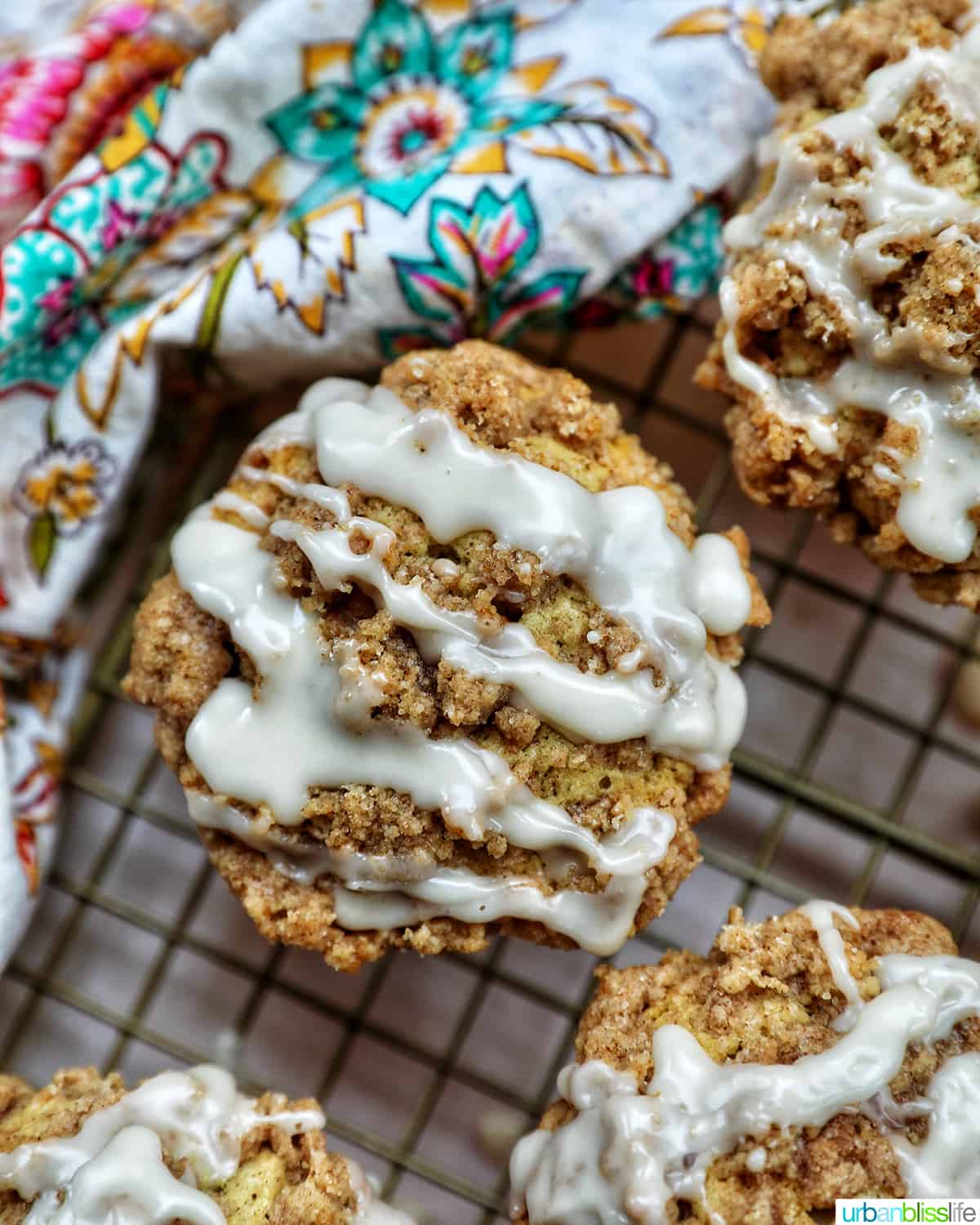 several vegan cinnamon streusel muffins on a wire rack with a colorful floral napkin.