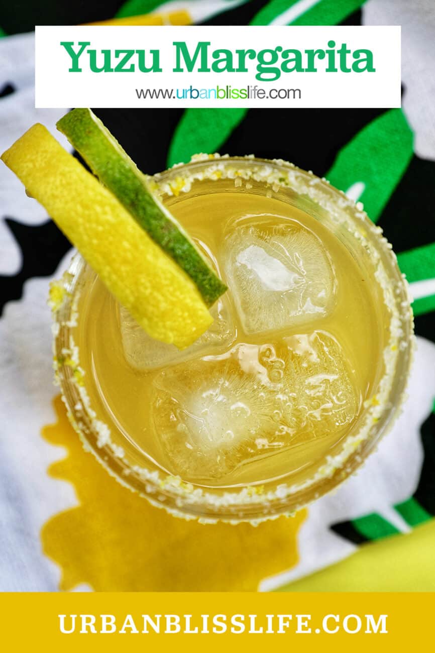 glass of yuzu margarita with slices of lemon and lime on brightly colored napkins with title text.
