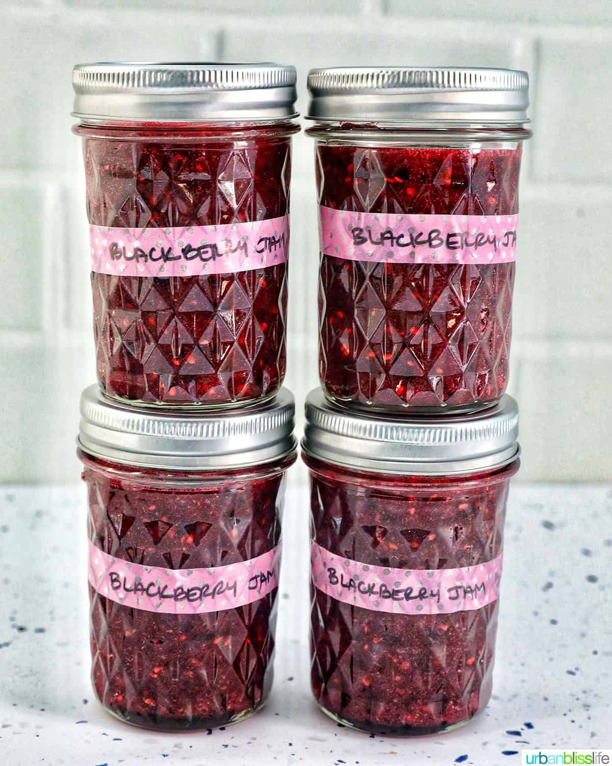 four mason jars of blackberry freezer jam, stacked.