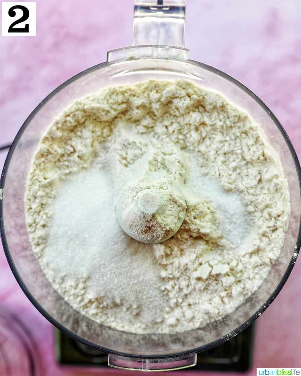 pie dough ingredients in a food processor on pink background.