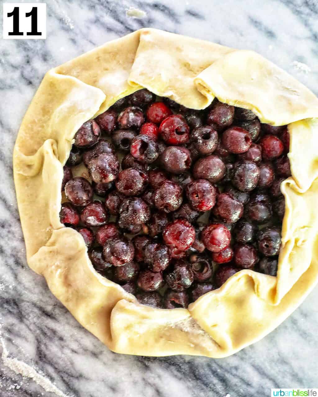 unbaked cherry galette on a marble countertop.