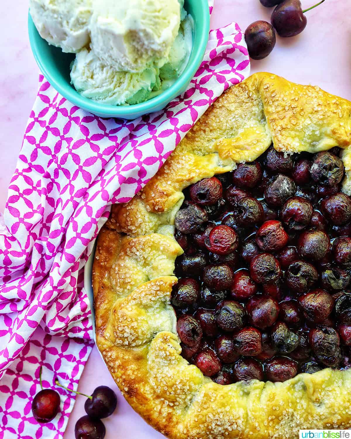 cherry galette on a plate with ice cream in a blue bowl.