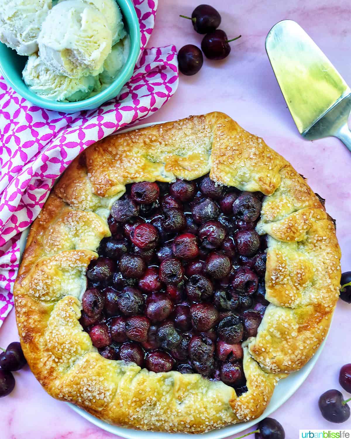 cherry galette with side bowl of ice cream scoops and pie server.