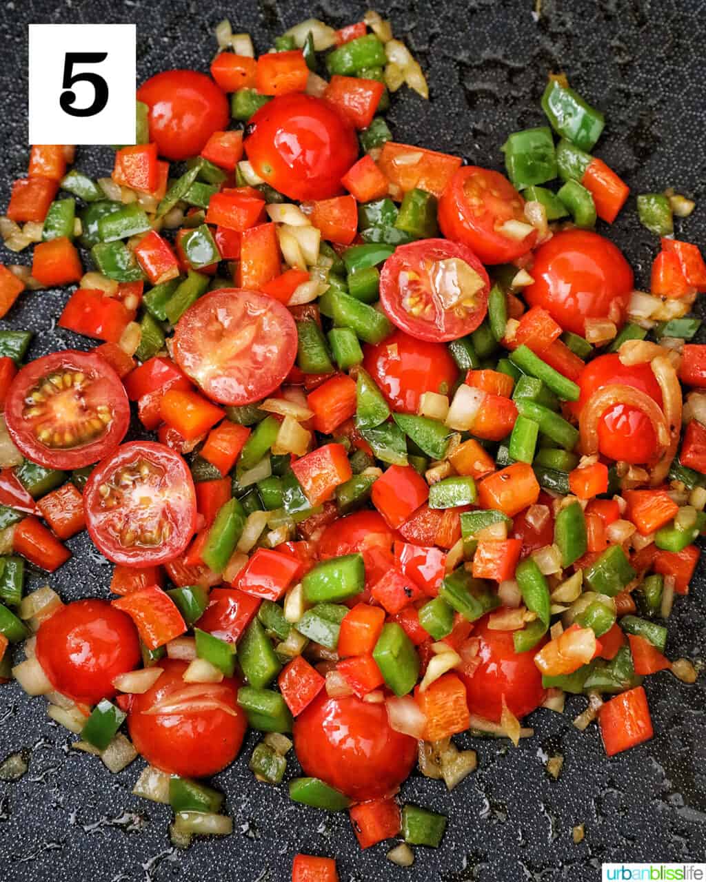 cherry tomatoes, garlic, onions, red bell peppers and green bell peppers in a skillet.