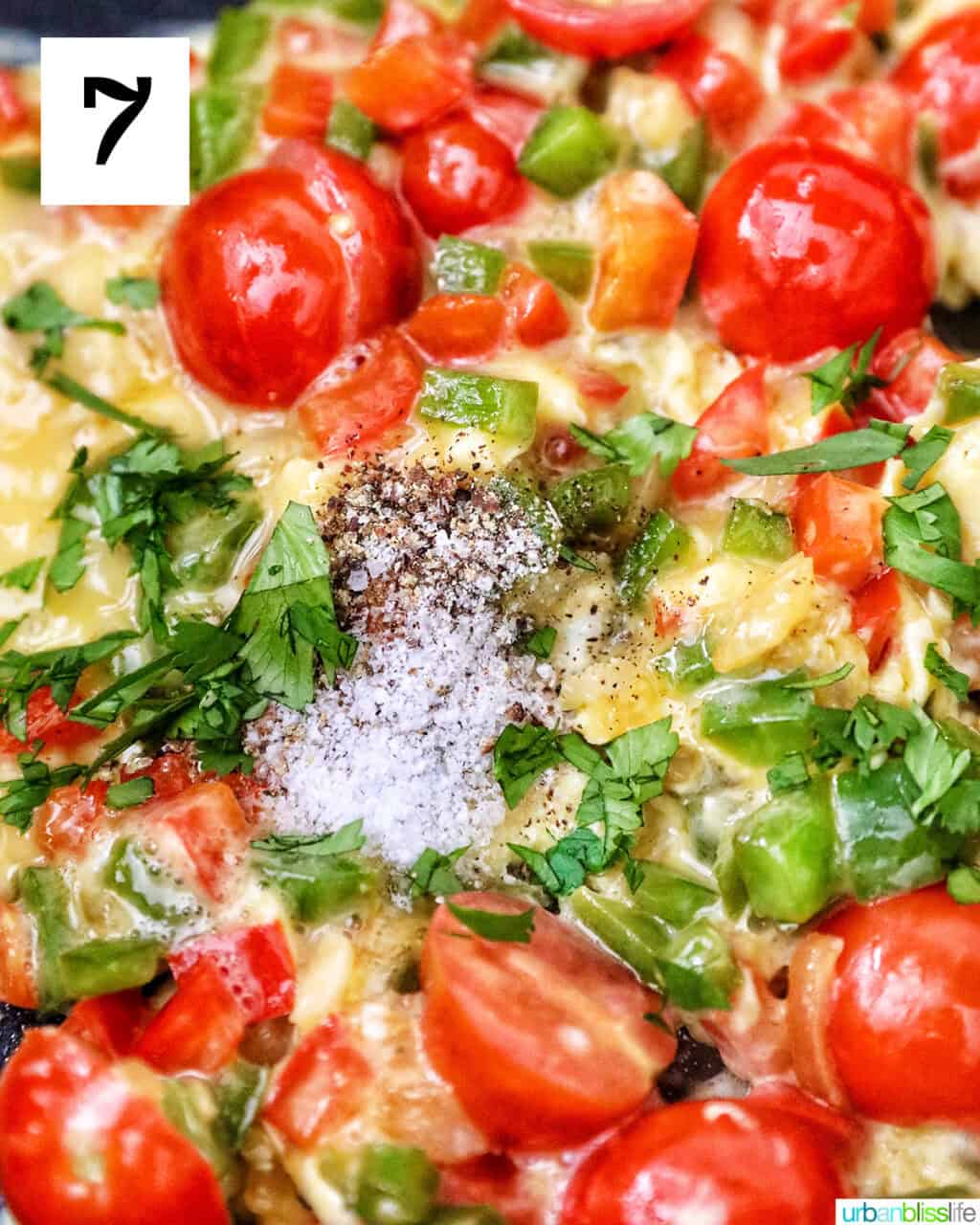 egg with cherry tomatoes, garlic, onions, red bell peppers and green bell peppers in a skillet.