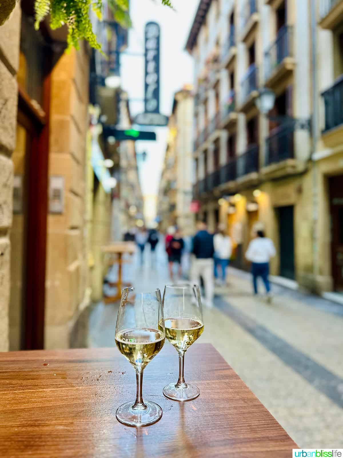 two glasses of txakoli on a table in a street in San Sebastian, Spain.