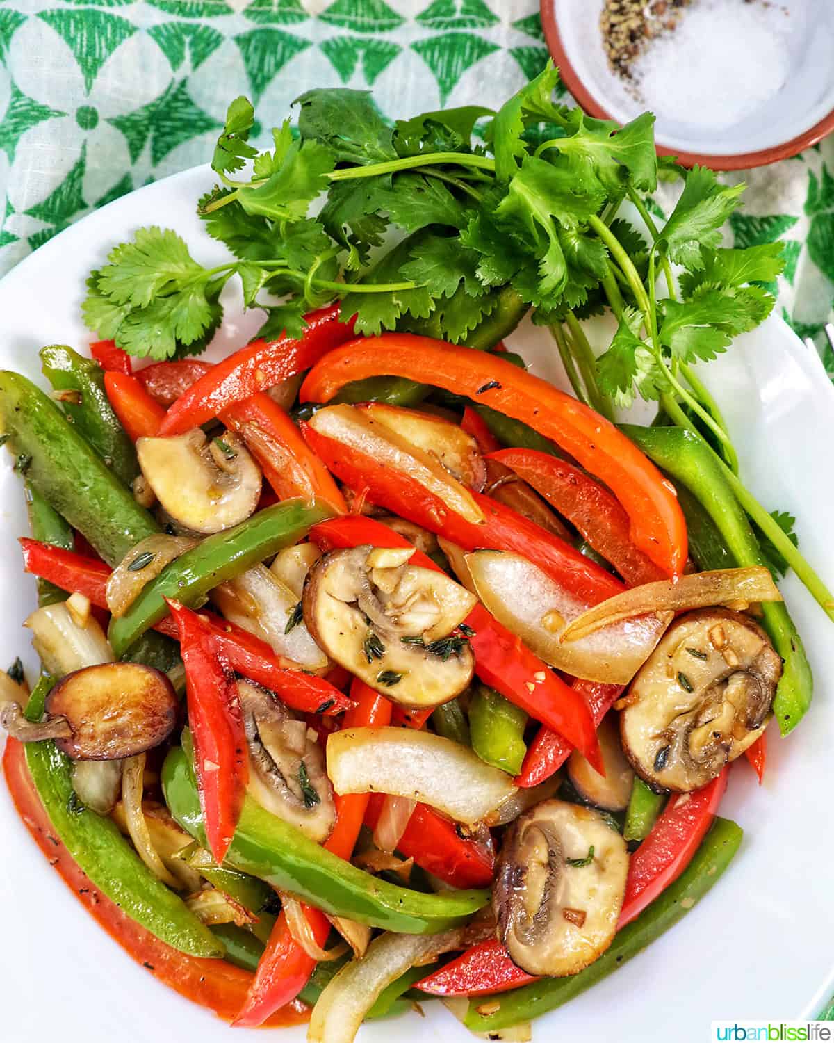 sautéed peppers and onions in a white bowl with garnish of parsley.