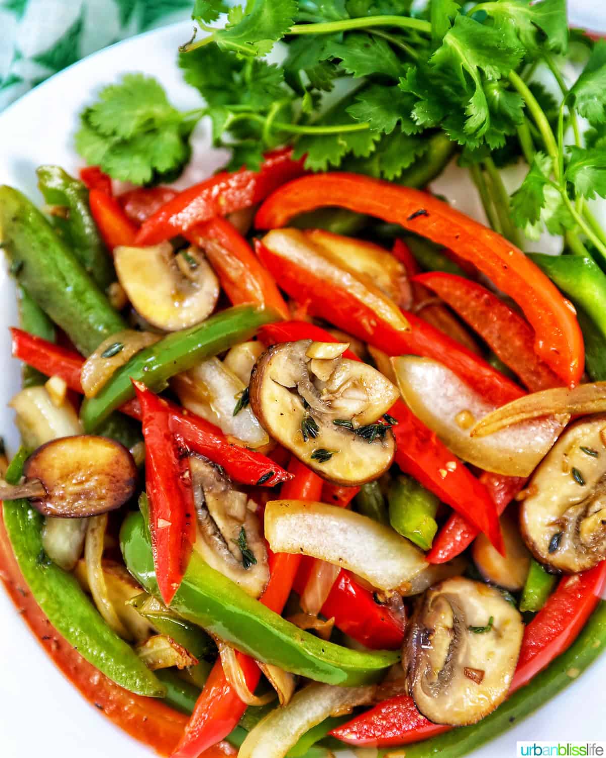 sautéed peppers and onions in a white bowl with garnish of parsley.