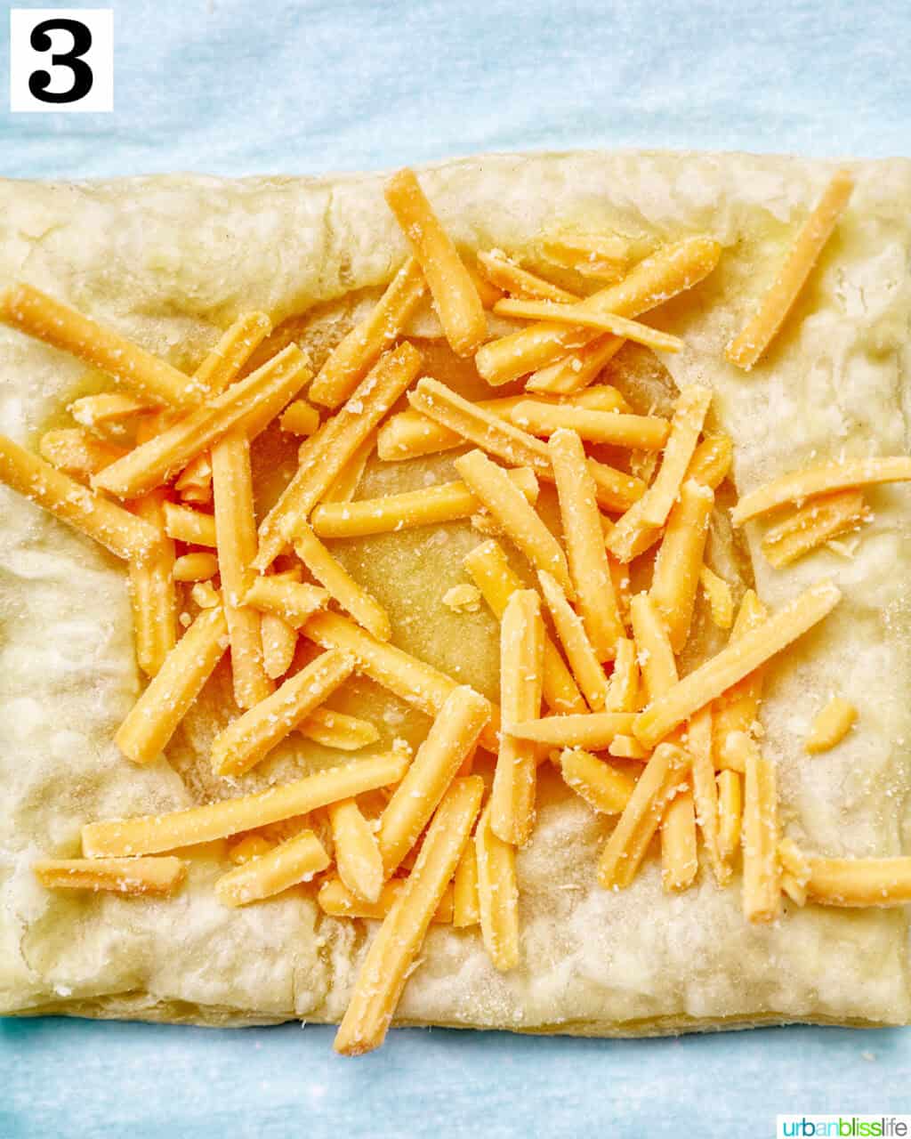 shredded cheddar cheese on puff pastry.