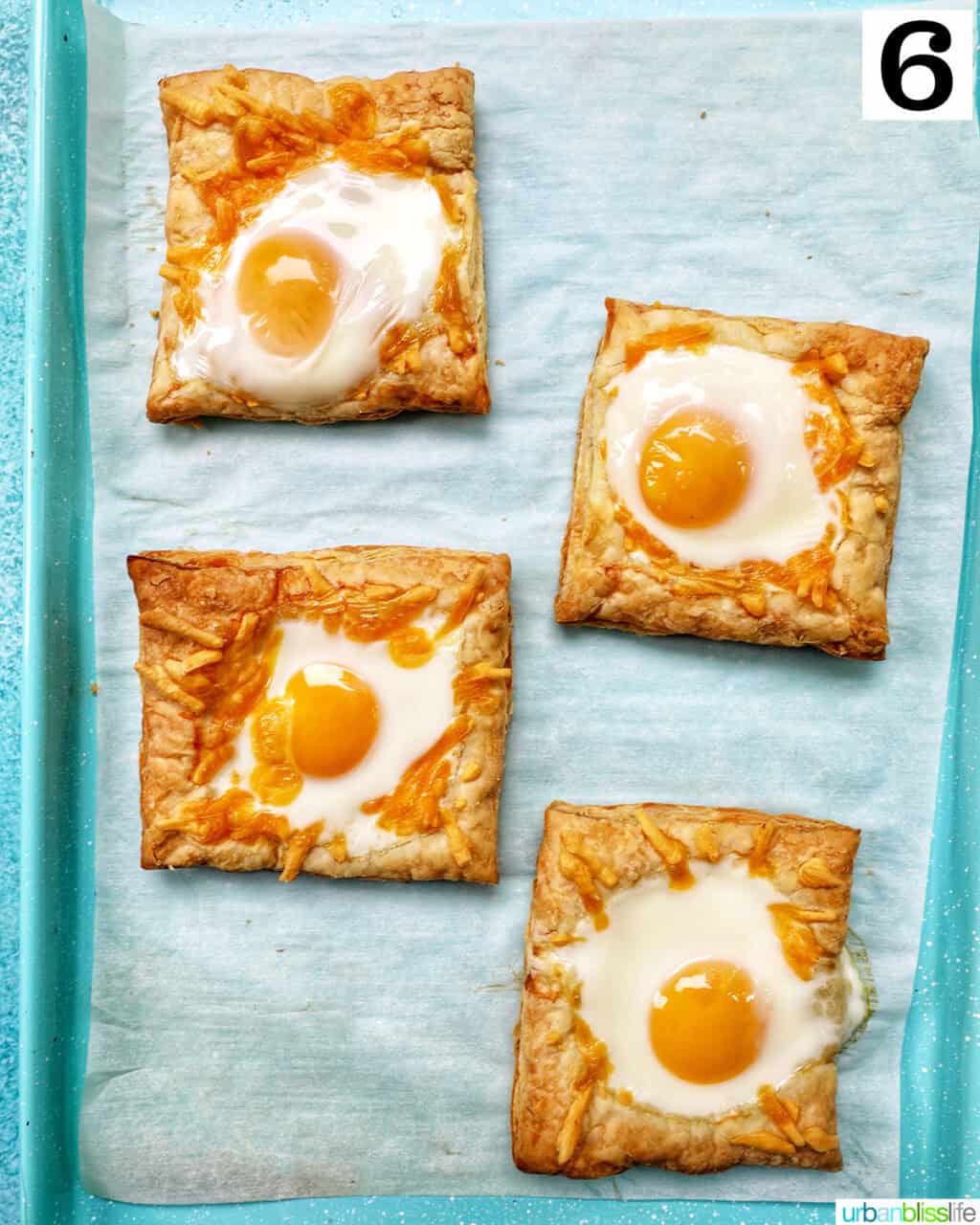 eggs baked in enter of puff pastry squares on a baking sheet.