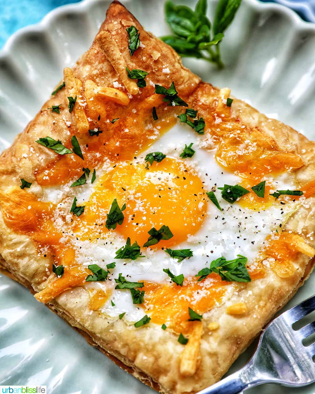 egg in puff pastry on a plate with parsley garnish.