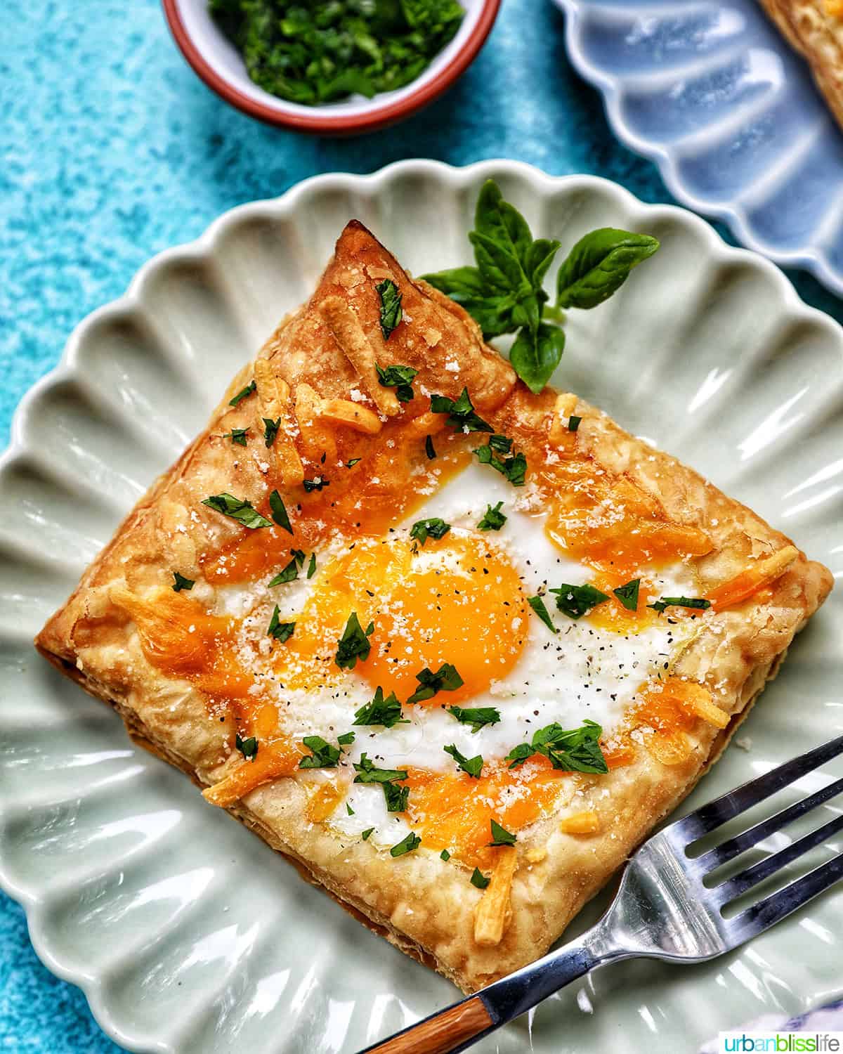 egg in puff pastry on a plate with parsley garnish.