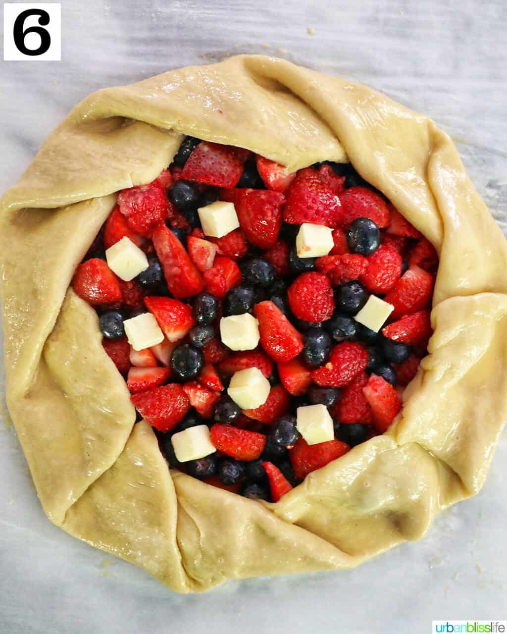 mixed berries in the center of pie dough on parchment paper.
