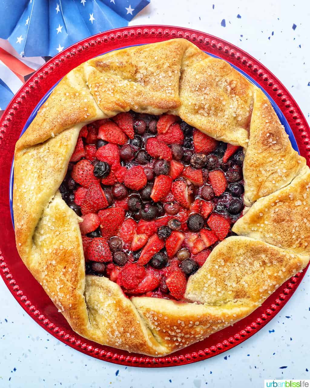 a mixed berry galette: mixed berries in pie dough on a red plate.