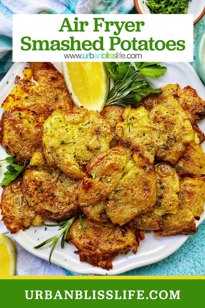 air fryer smashed potatoes on a plate with lemon wedges and herbs.