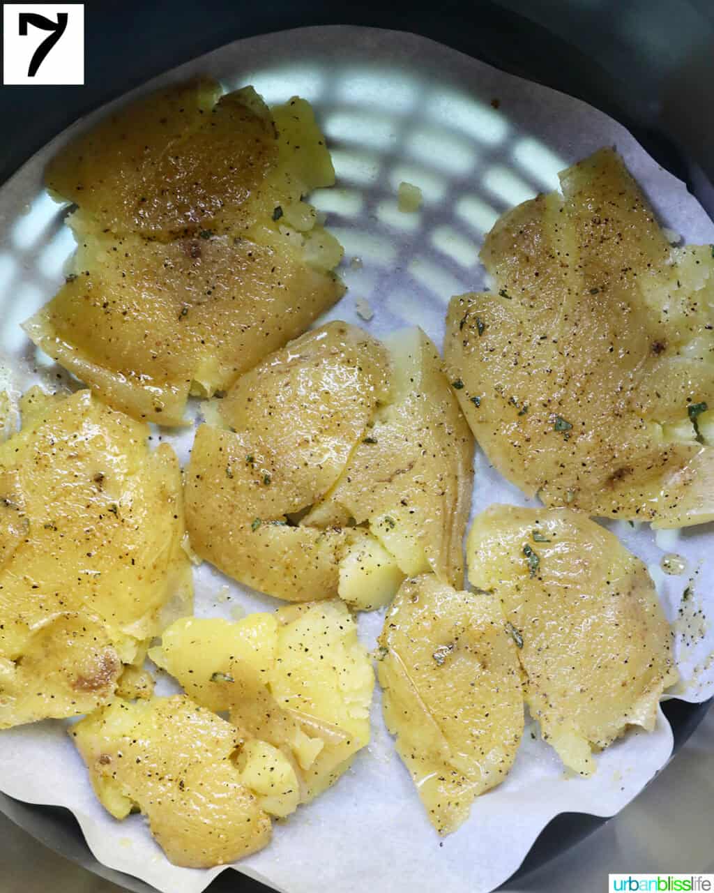 raw potatoes smashed in an air fryer basket.