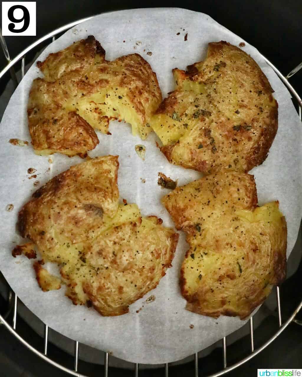 four smashed potatoes in an air fryer basket.