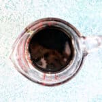 measuring cup of balsamic glaze on a blue background.