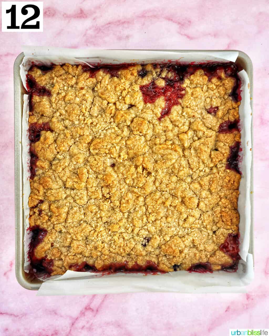cherry crumble bars in a baking pan on pink background.
