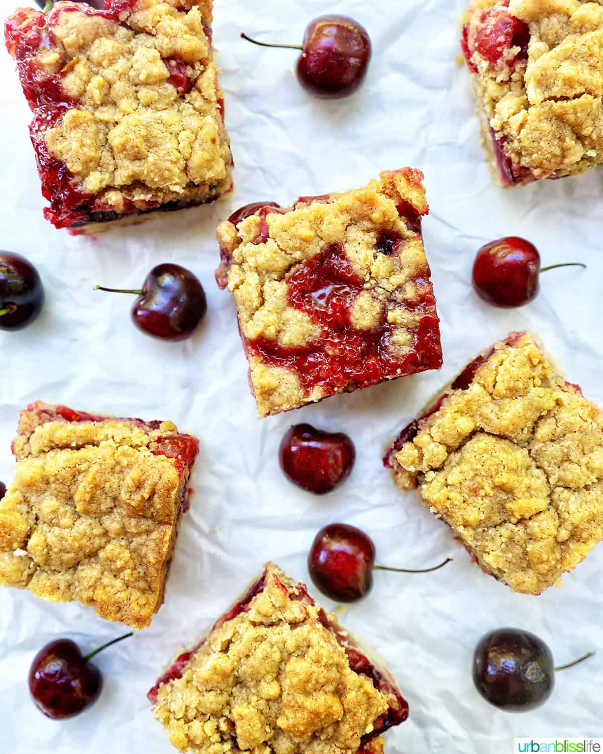 several cherry crumble bars surrounded by cherries.