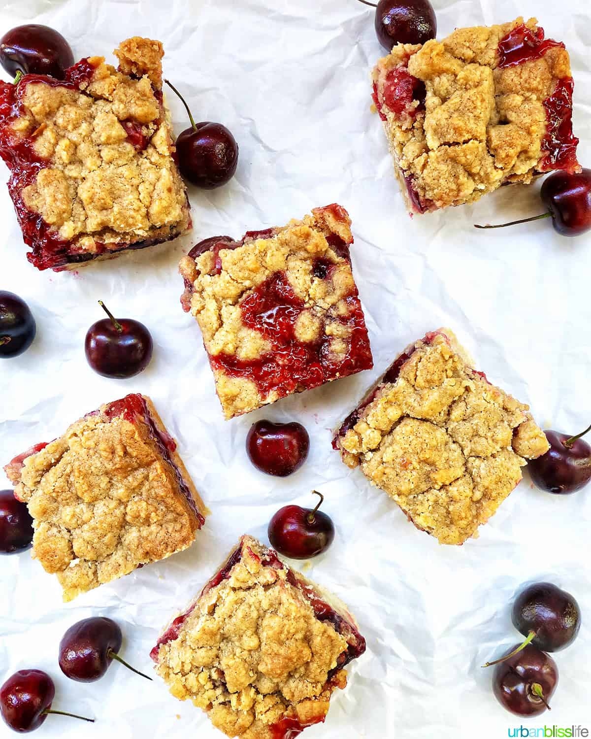 several cherry crumble bars surrounded by cherries.