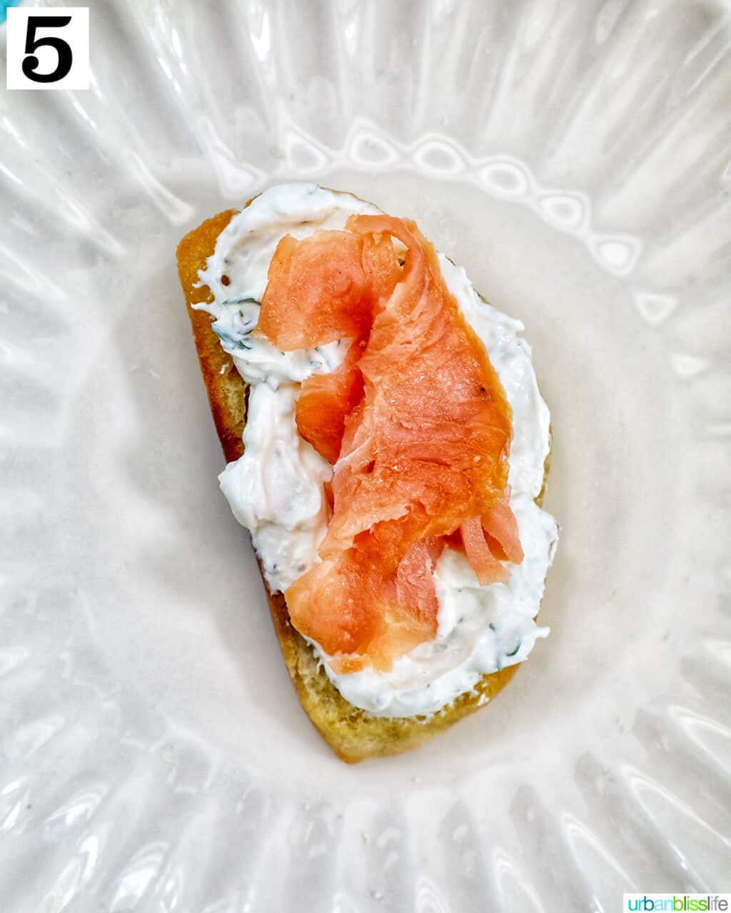 single crostini on a plate with cream cheese and smoked salmon.