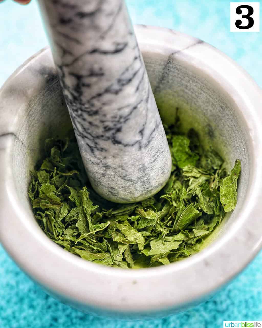 mortar and pestle crushing dried mint leaves.