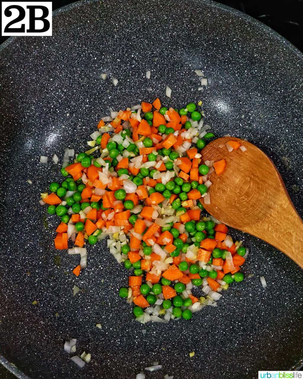 wok with vegetables and a wooden spoon.