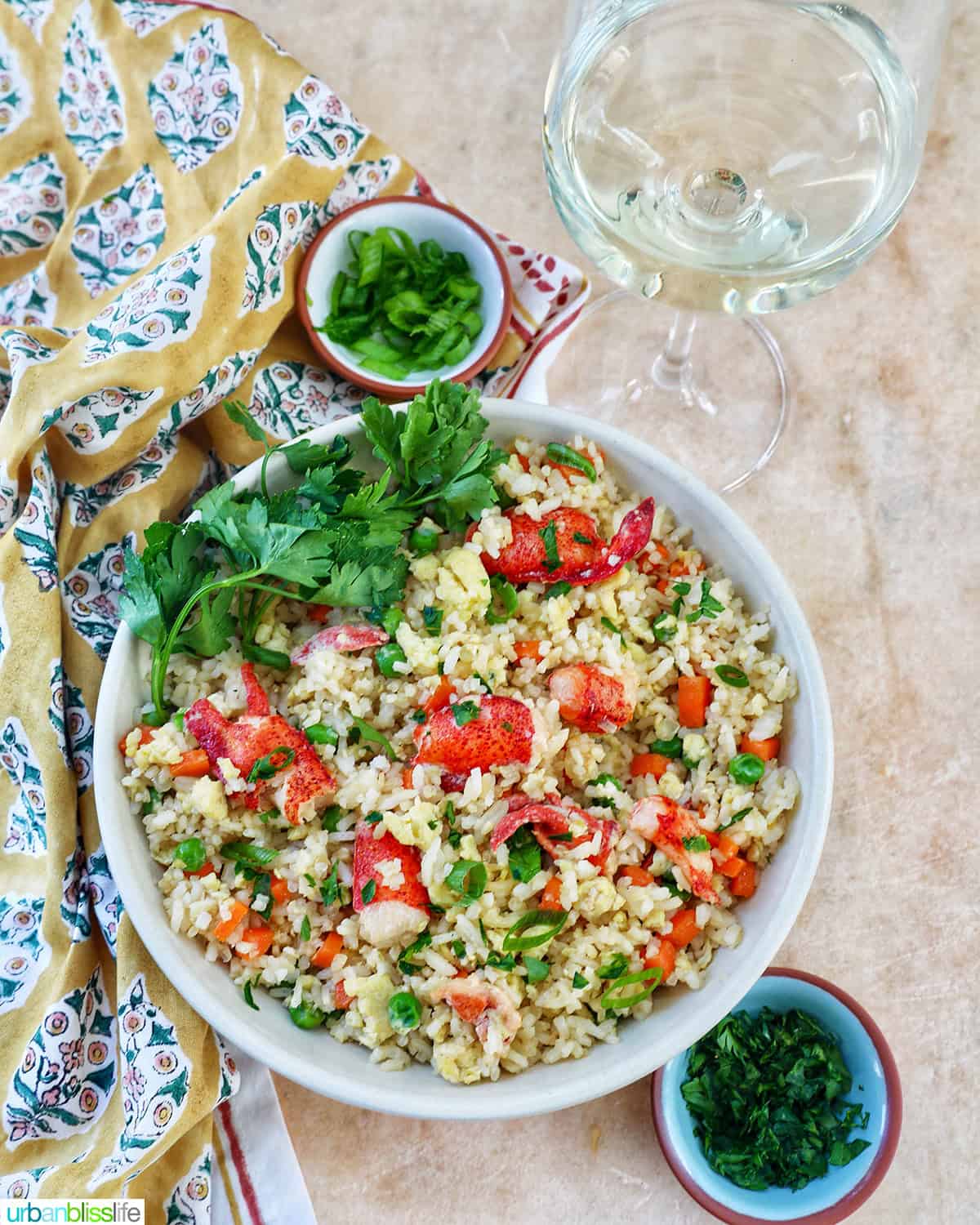 bowl of lobster fried rice with bowls of fresh herbs and a glass of white wine.