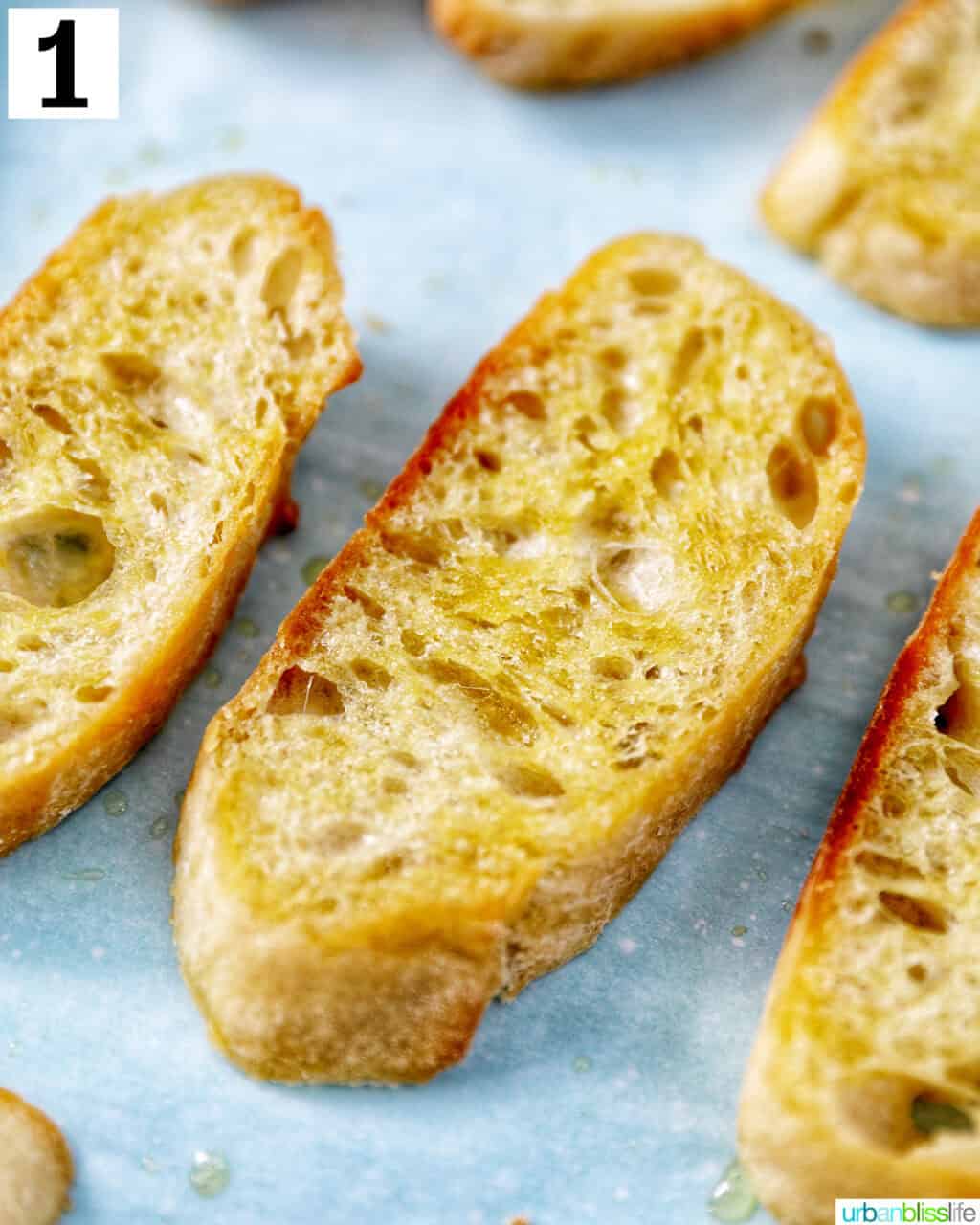 closeup of sliced baguette with olive oil on a baking sheet.