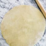 rolled out pie on marble next to a rolling pin.