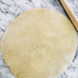 rolled out pie on marble next to a rolling pin.