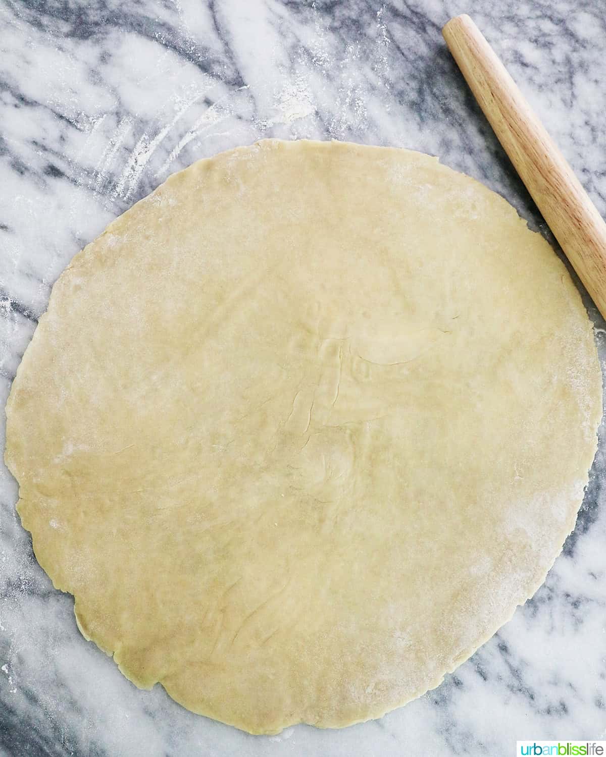 rolled out pie on marble next to a rolling pin.