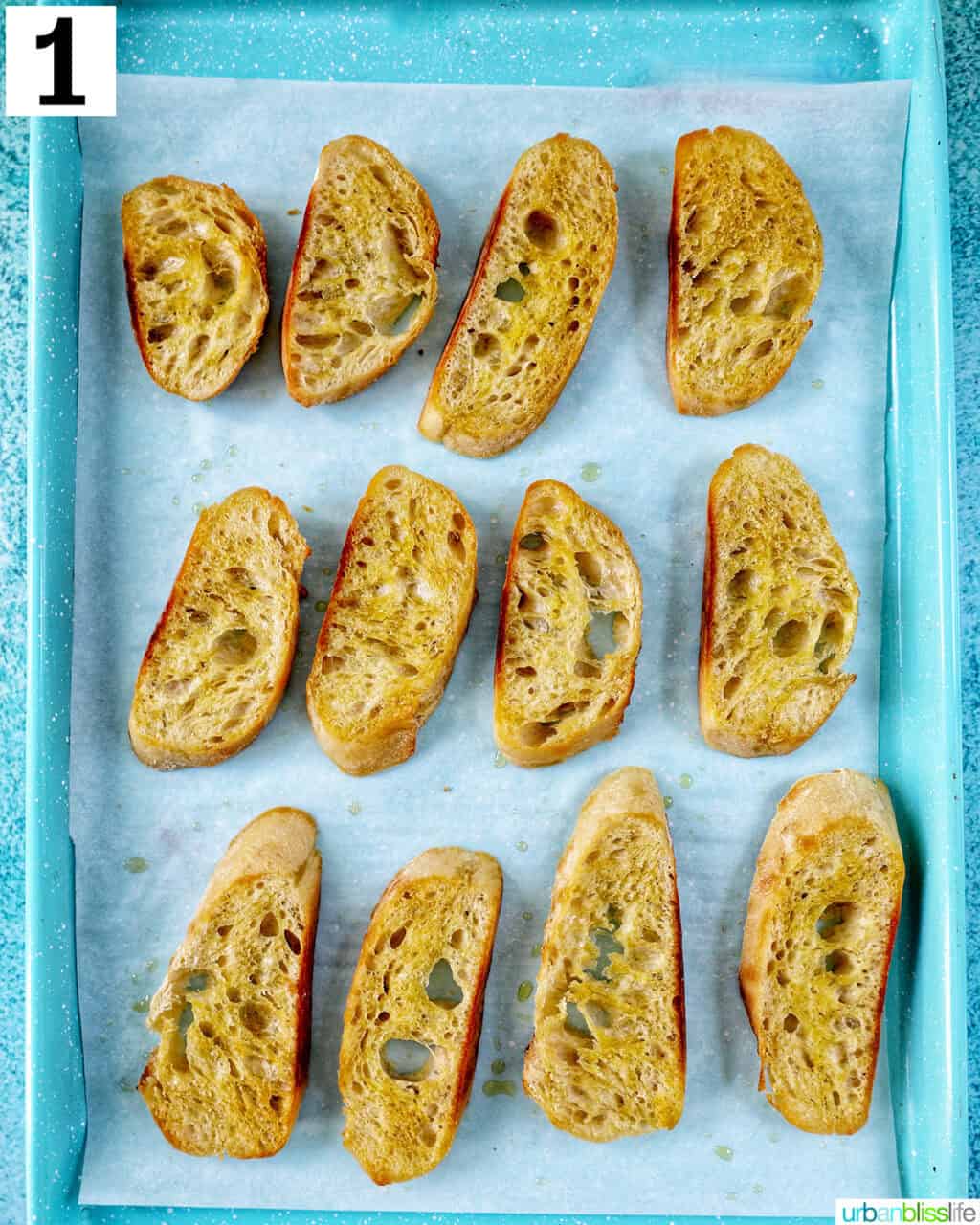 sliced baguette on a parchment paper-lined baking sheet.