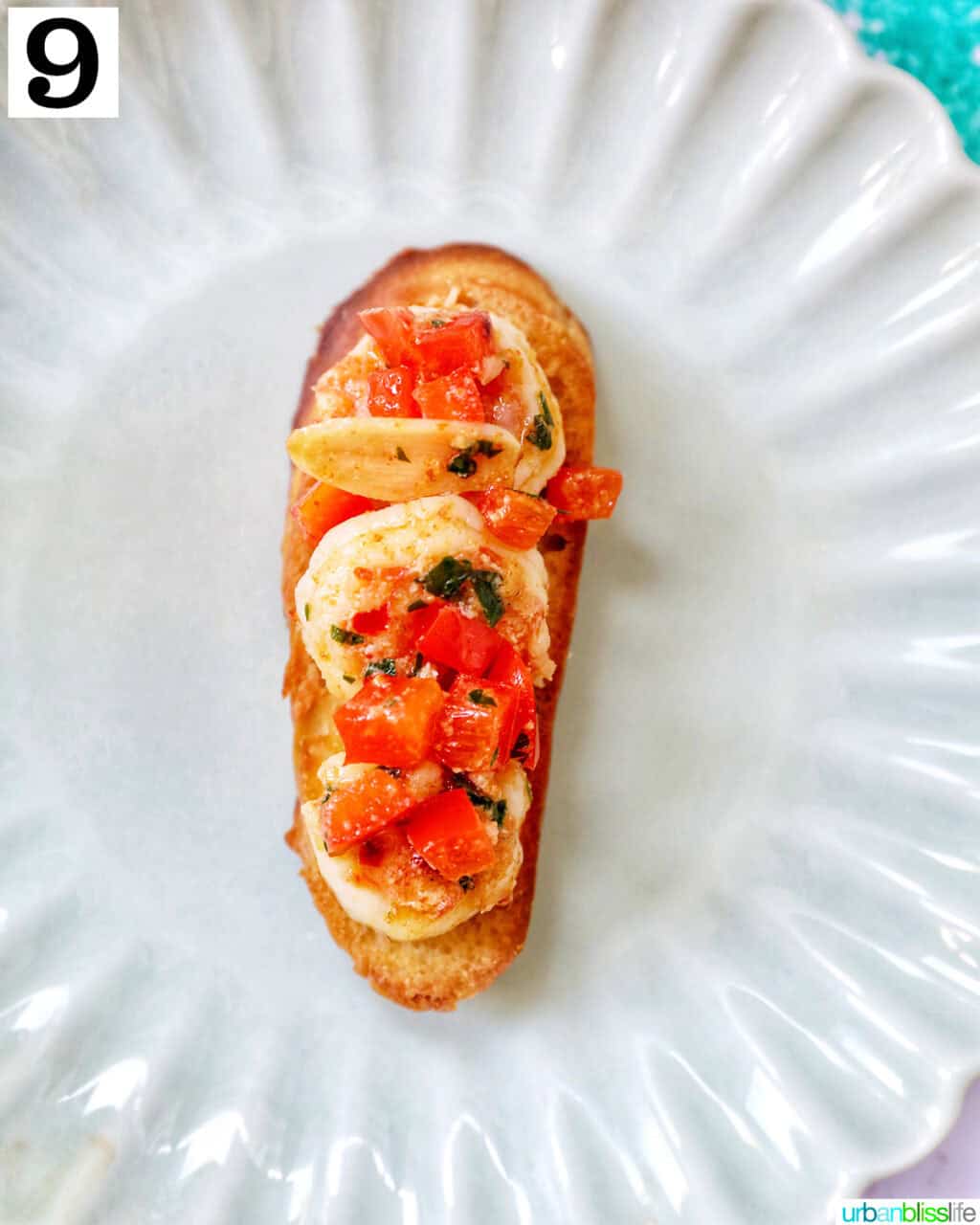 shrimp pintxos skewers with tomatoes on crostini bread on a scalloped plate.