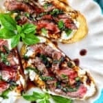 steak crostini with fresh basil leaves as garnish on a plate.