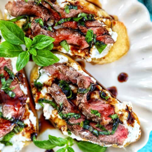 steak crostini with fresh basil leaves as garnish on a plate.