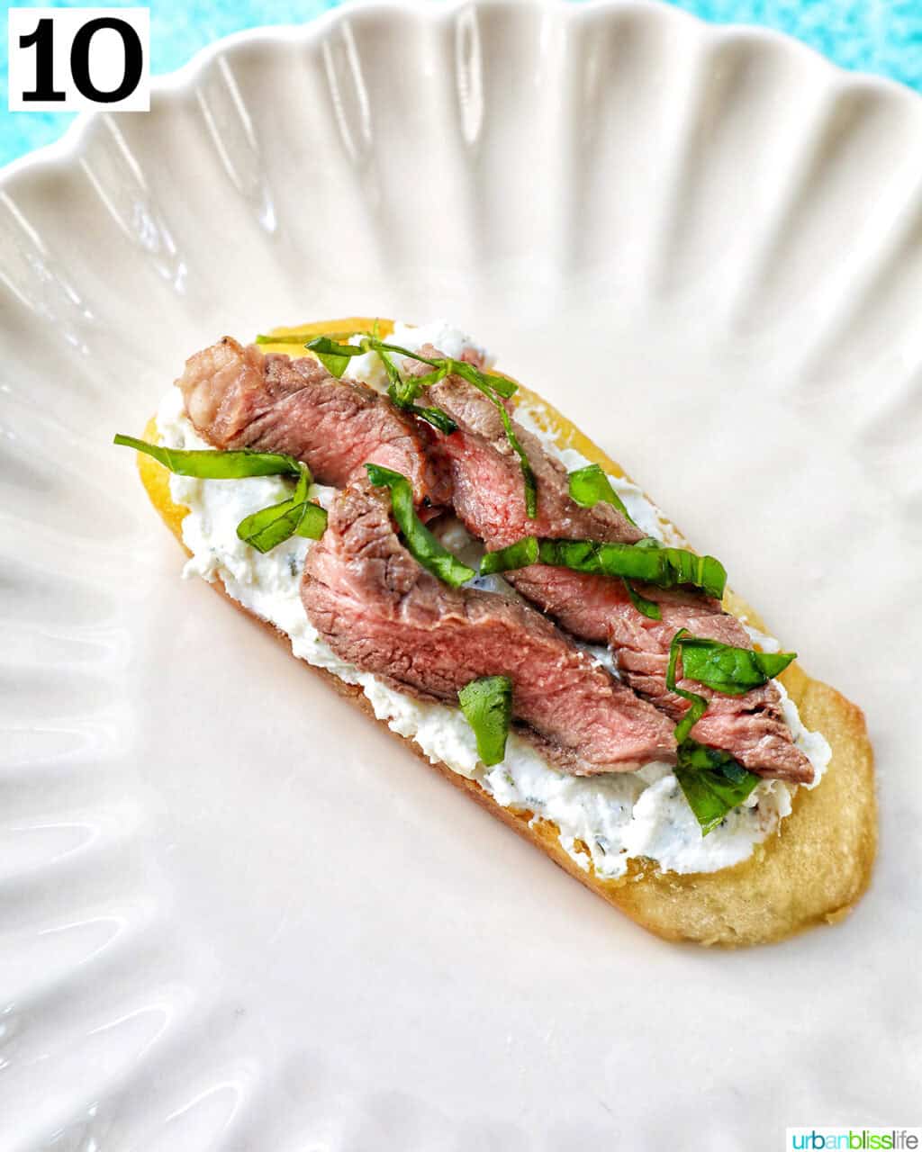 single steak crostini on a plate.