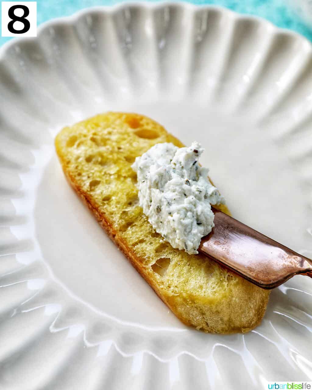 adding goat cheese spread to a crostini on a plate.