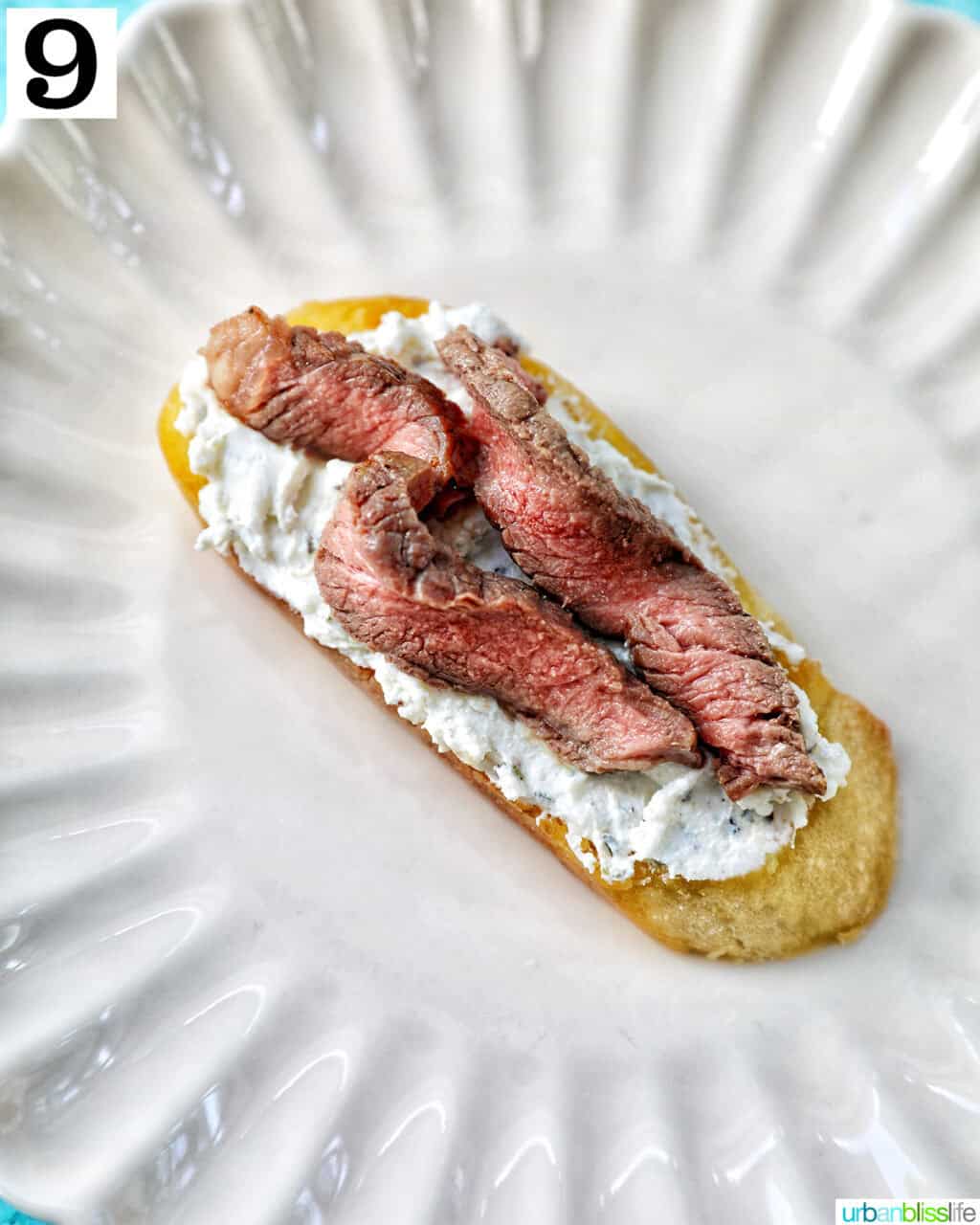 steak strips added to crostini on a plate.