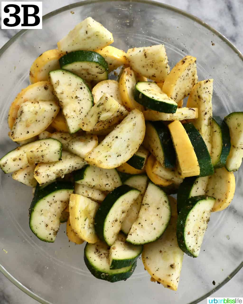sliced zucchini and yellow squash coated with oil and herbs in a bowl.