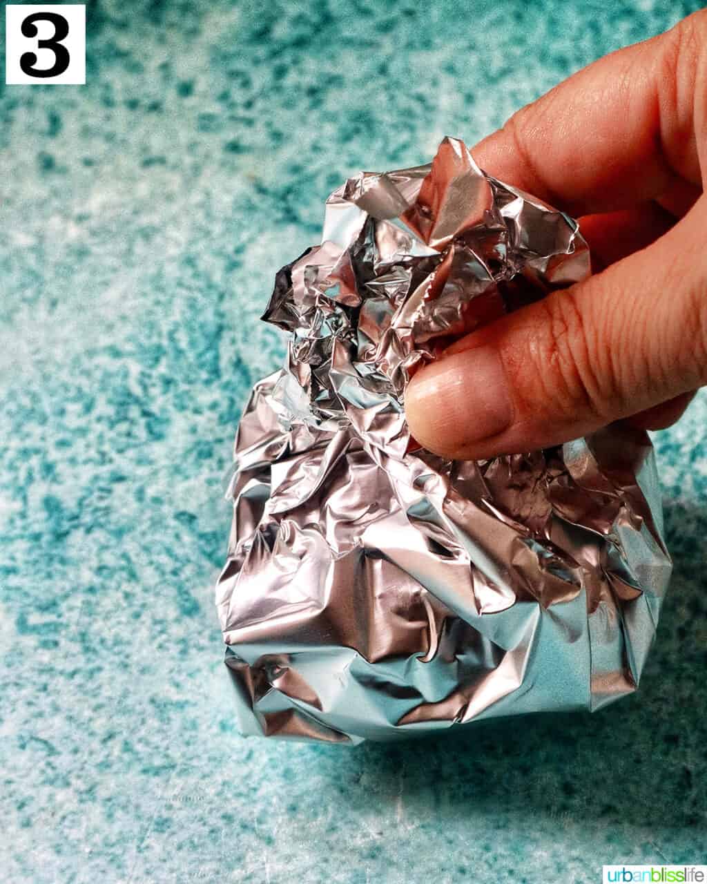 hand holding aluminum foil pack of garlic head.