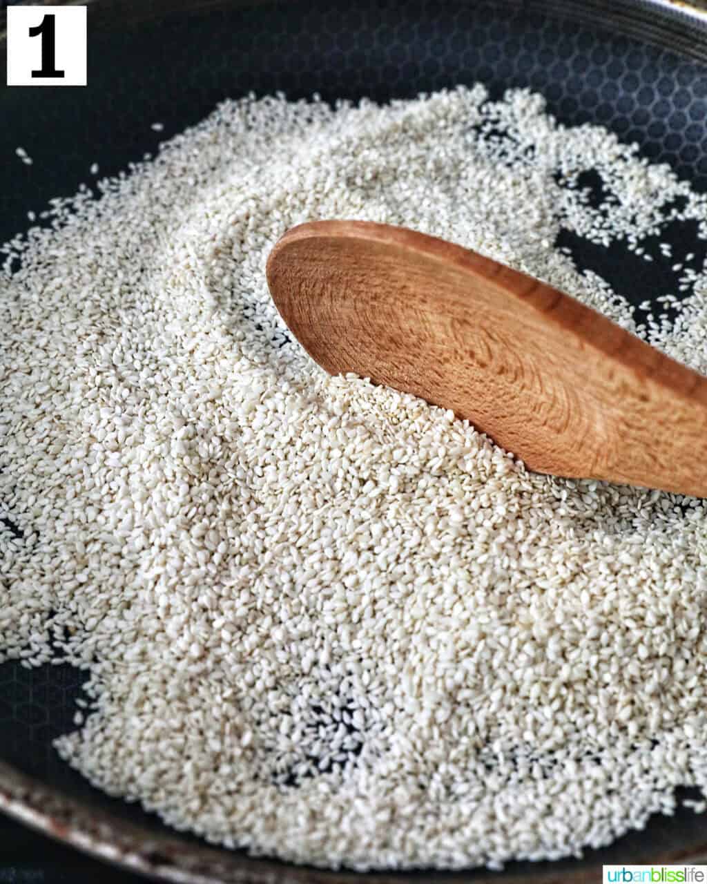 wooden spoon with sesame seeds toasting in a pan.