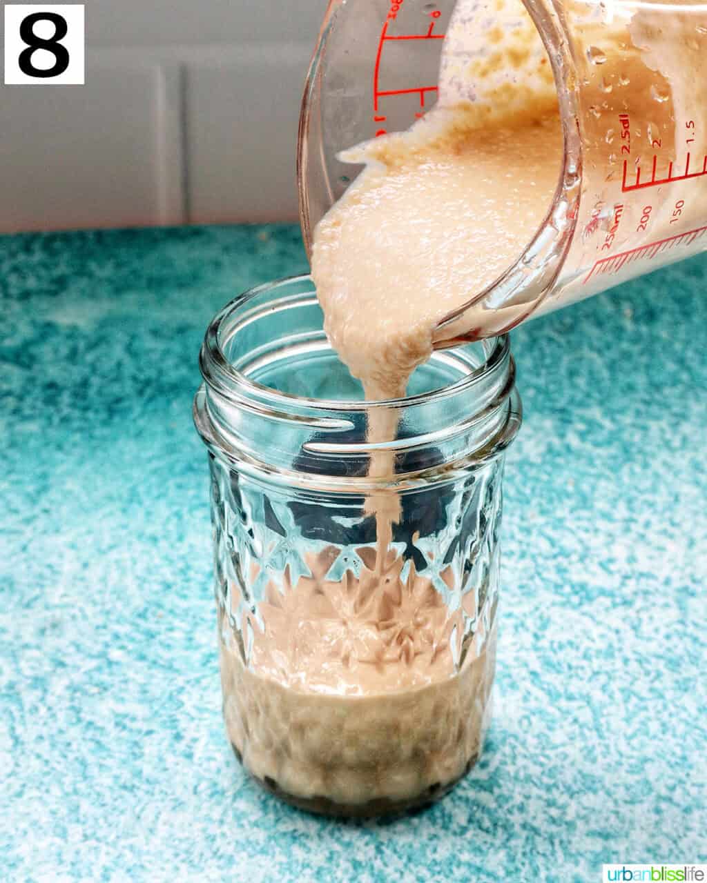 pouring homemade tahini into a mason jar.