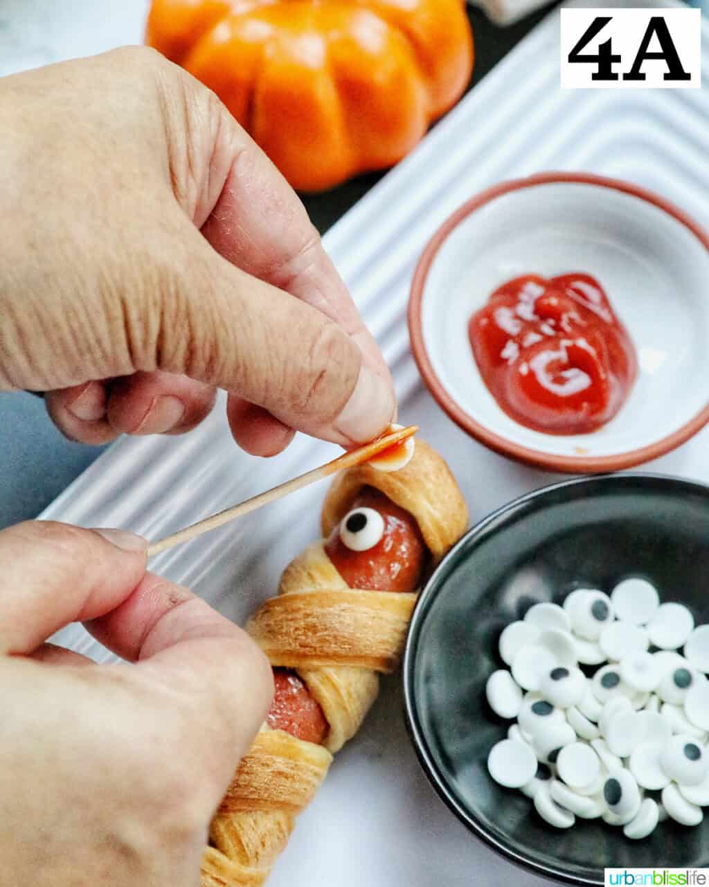 adding candy eyes to a mummy dog.